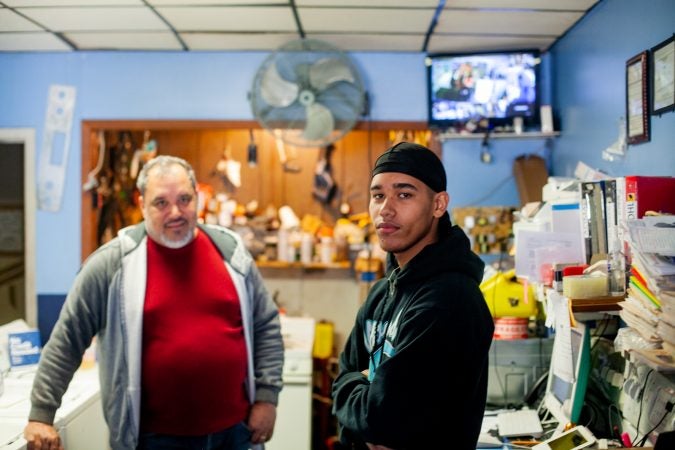 Rolando Rivera, 15, and his father, Javier, inside the Pronto appliance shop, their family business, on Torresdale Avenue in the Tacony section of Philadelphia. (Brad Larrison for WHYY)