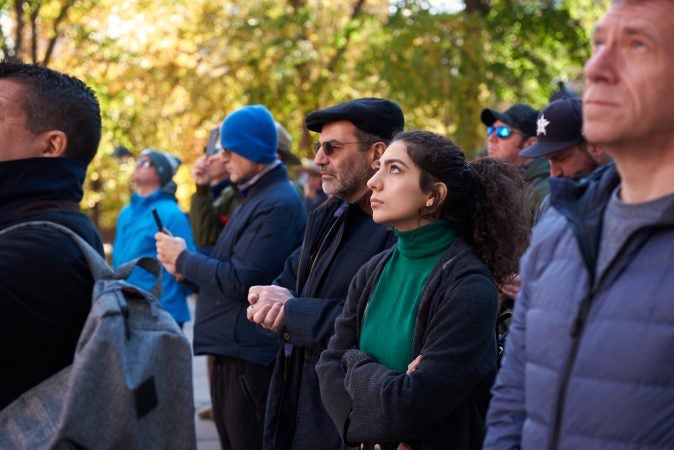 Guita Vahdatina, a resident of California, stands to watch the bell ring at Independence National Historical Park in Philadelphia on the centennial anniversary of Armistice Day on Nov. 11, 2018. (Natalie Piserchio for WHYY)