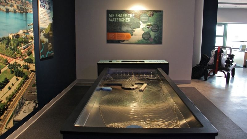 With the watershed modeling table, visitors can interrupt and direct the flow of water, exploring the ways humans alter the course of water for their own uses. (Emma Lee/WHYY)