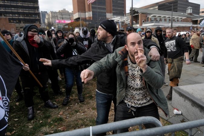 Two unidentified males attempt to hold off counter-protestors across from the 