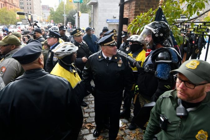 Police officers request Alan Swinney to return to a fenced area after the  protester attempt to interact with counter-protesters on the corner of 5th and Market streets, during the 