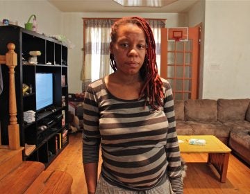 Sherri Lee stands in the living room of her rented home on Snyder Avenue. Plumbing issues there have forced her to seek another home for her family, which includes five children. (Emma Lee/WHYY)