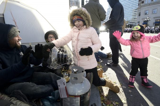 A gas powered heater keeps members of the Gibbons and Eggleston families of Drexel Hill, PA warm as they watch the 99th annual Thanksgiving Day Parade, in Center City Philadelphia. (Bastiaan Slabbers for WHYY)