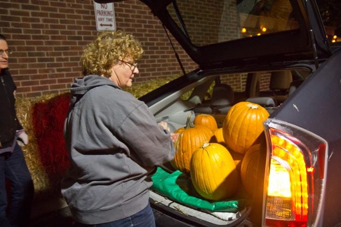 Steve Levy and Lucia Kubik load pumpkins into their car during a donation pickup around South Philadelphia. (Kimberly Paynter/WHYY)