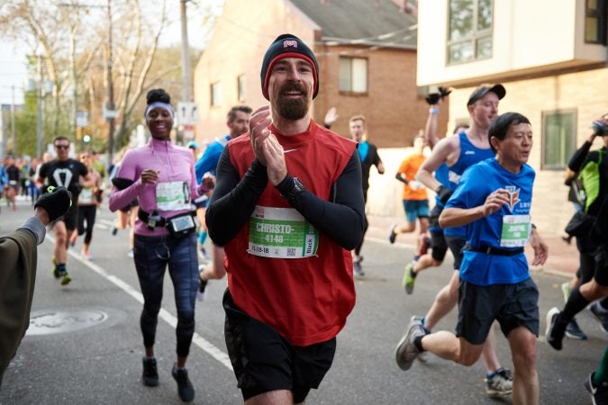 Participants of the 2018 Philadelphia Marathon pass the Mother Bethel A.M.E. Church Choir with waves and smiles as they make their way up Sixth street on Sunday Nov. 18, 2018. (Natalie Piserchio for WHYY)