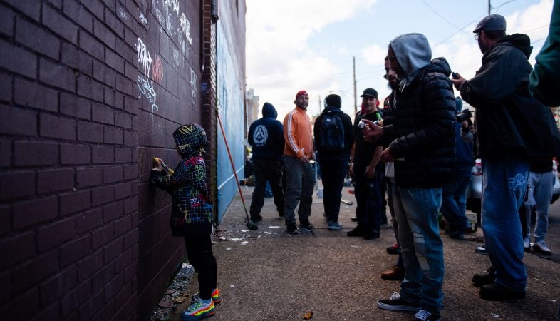 Silas, age 5, adds his own art to a wall tagged by other writers during a memorial and mural paiting dedicated to Karaz on Saturday, November 3, 2018. (Kriston Jae Bethel for WHYY)