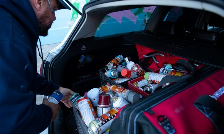 Spray paint used for a mural dedicated to Philadelphia
graffiti writer Karaz fills the trunk of a car on Saturday, November 3, 2018. (Kriston Jae Bethel for WHYY)