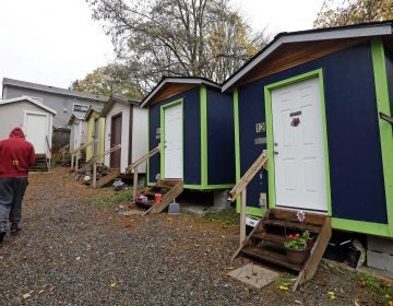 In this 2017 photo, a resident walks past a row of tiny houses at a homeless encampment in Seattle. (Elaine Thompson/AP Photo, file)