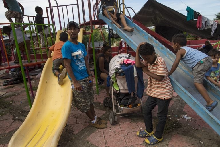 Joel Eduardo Espinar, (left), and his son, Jason, 11, wait at their chosen campsite in the main square of Tapanatepec, Mexico, on Oct. 28, 2018. His plan is to request asylum rather than cross the U.S. border illegally. 