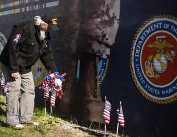 Veteran Patrick Watson places a wreath at the base of a new Mural Arts Philadelphia piece titled 