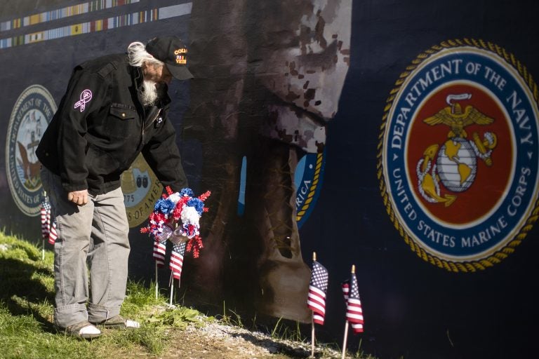 Veteran Patrick Watson places a wreath at the base of a new Mural Arts Philadelphia piece titled 