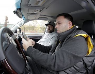 In a photo taken Friday, Nov. 9, 2018, in Bayonne, N.J., Lenny Sciascia, (right), and his friend Mario DeAngelis look at betting lines for the day's sporting events before placing bets in a parking lot just off the Bayonne Bridge, which divides New York and New Jersey. Sciascia, who lives in Staten Island, N.Y., commutes regularly to places his bets from New Jersey, where online betting is legal. With sports betting being advertised all around them but the opportunity to actually do it restricted to just one nearby state, gamblers from New York and Pennsylvania are crossing bridges and tunnels into New Jersey to make legal sports bets. (Julio Cortez/AP Photo)