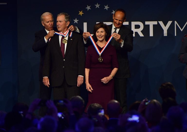 Former U.S. Vice President Joe Biden, from left, bestows a medal on former U.S. President George Bush as former first lady Laura Bush has the same bestowed by Doug DeVos, executive committee chairman for the National Constitution Center, at the National Constitution Center, Sunday, Nov. 11, 2018 in Philadelphia. Both received the 30th annual Liberty Medal, an honor given to those who are committed to freedom and human rights globally. (AP Photo/Corey Perrine)