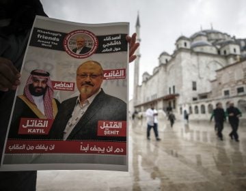 A man holds a poster showing images of Saudi Crown Prince Muhammed bin Salman and of journalist writer Jamal Khashoggi, describing the prince as 