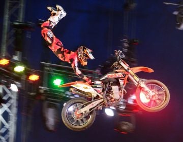 A performer on a motorbike kicks their feet in the air