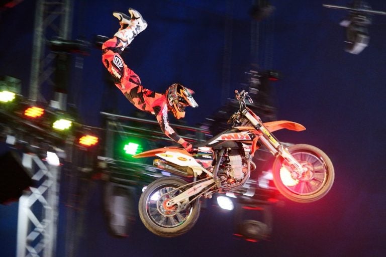 A performer on a motorbike kicks their feet in the air
