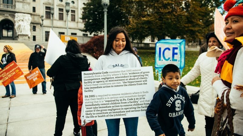 Adamaris Lopez of Philadelphia holds a sign with text excerpts of legal arguments from the Sheller Center for Social Justice of the Temple University Beasley School of Law. She joined a protest outside the Pennsylvania Capitol organized around the work of muralist Michelle Angela Ortiz. (Dani Fresh fpr WHYY)