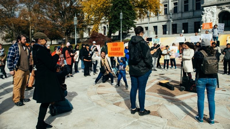 A young boy in a Captain America costume and a woman pose for a photo in front of the Capitol as Ortiz speaks during the rally on Saturday. (Dani Fresh for WHYY)