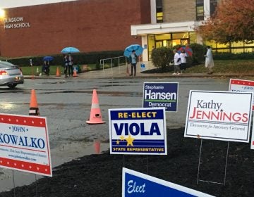 Poll workers carry umbrellas as they greet voters headed in to a polling place at Glasgow High School on Tuesday, Nov. 6. (Mark Eichmann/WHYY)