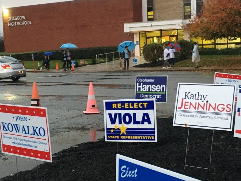 Poll workers carry umbrellas as they greet voters headed in to a polling place at Glasgow High School on Tuesday, Nov. 6. (Mark Eichmann/WHYY)