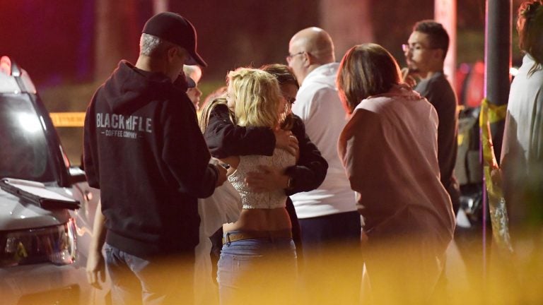 People comfort each other outside a bar in Thousand Oaks, Calif., where a gunman opened fire and killed 12.