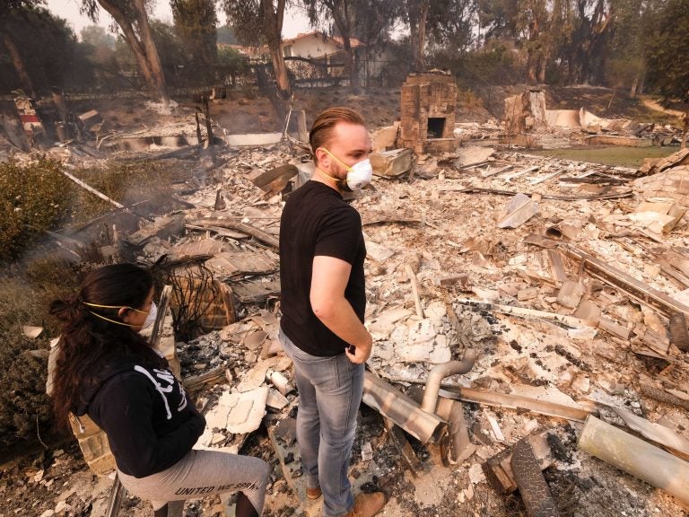 A California man and his girlfriend return to his burned out home in Malibu on Saturday. (Ringo H.W. Chiu/AP)