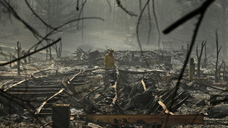 A firefighter searches a trailer park destroyed in the Camp Fire on Friday Paradise, Calif. (John Locher/AP)