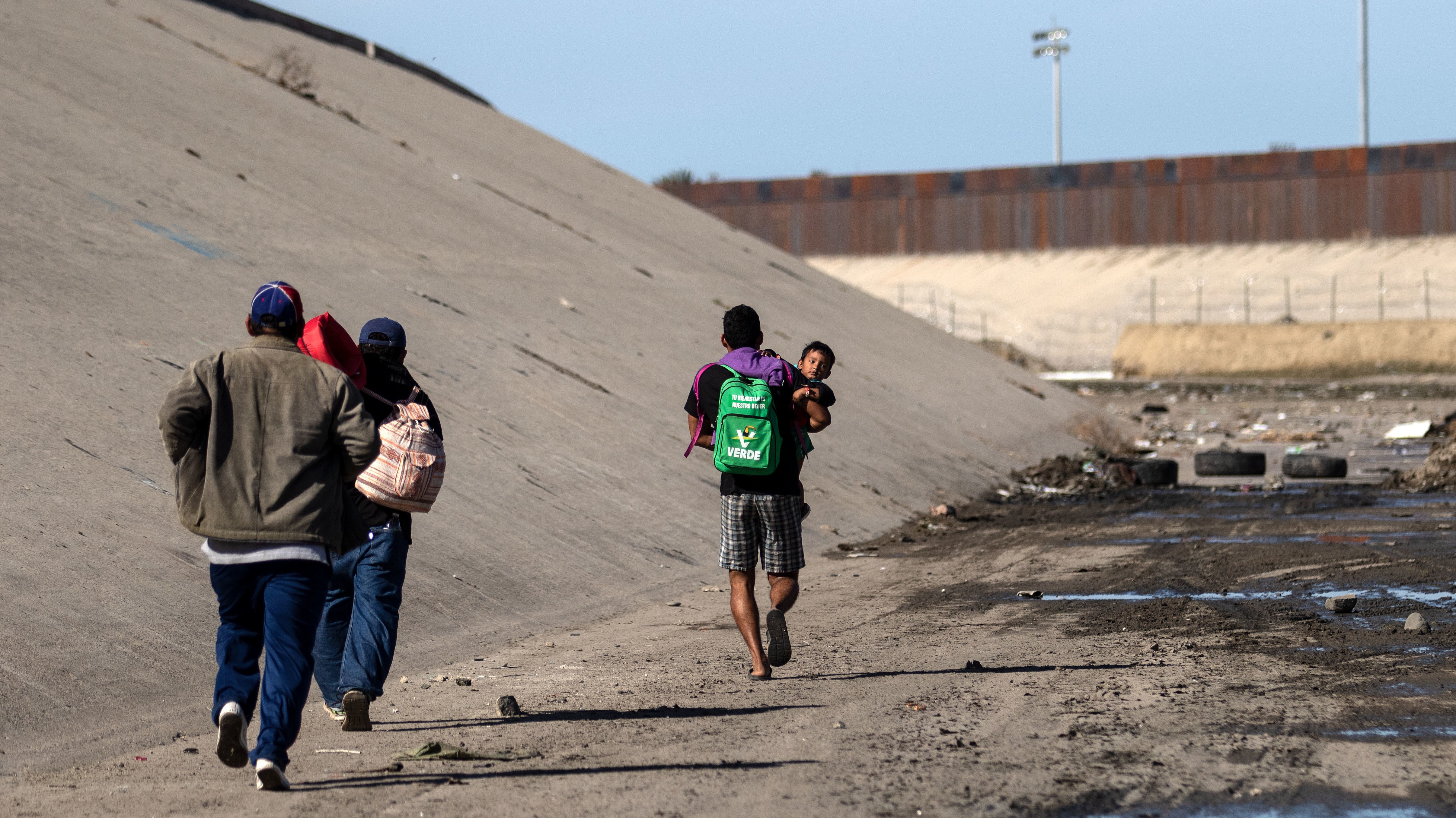 Central American migrants run along the shallow concrete waterway of the Tijuana River,in Tijuana, Mexico, on Sunday.