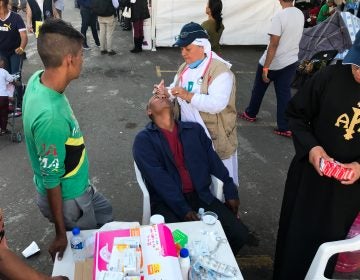 Sister Bertha Lopez Chaves applies anti-inflammatory eyedrops to a migrant at a stadium in Mexico City where the caravan is resting. Her order is one of roughly 50 groups giving aid to the migrants in the Mexican capital. 