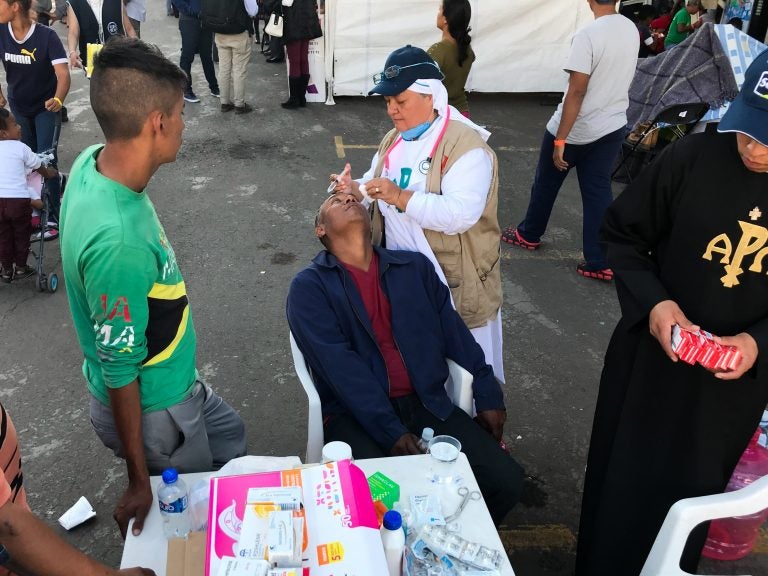 Sister Bertha Lopez Chaves applies anti-inflammatory eyedrops to a migrant at a stadium in Mexico City where the caravan is resting. Her order is one of roughly 50 groups giving aid to the migrants in the Mexican capital. 