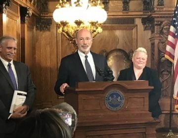 Governor Tom Wolf, flanked by outgoing budget secretary Randy Albright and his replacement, Jen Swails. (Katie Meyer/WITF)