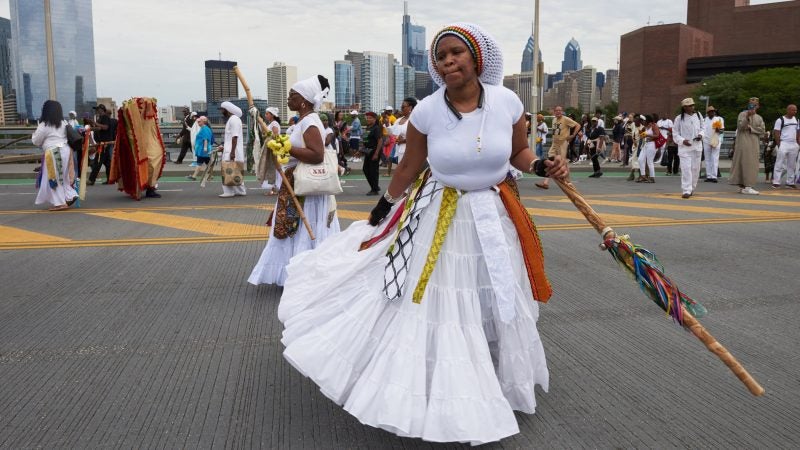 Yannie dances over the South Street Bridge before the procession to Oshun, the Goddess of the River, during the Odunde festival on June 10, 2018. (Natalie Piserchio for WHYY)