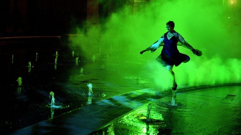 Artist Janet Echelman twirls in the mist during the public unveiling of the first section of the site-specific art installation titled Pulse at the Dilworth Park’s fountain, on Sept. 12, 2018. (Bastiaan slabbers for WHYY)