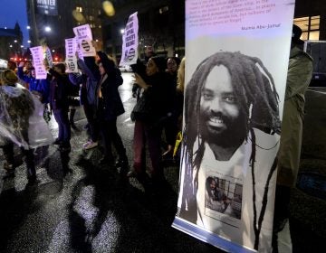 A group of two dozen activists briefly blocks traffic during a rally outside the Philadelphia district attorney’s office in December. The group is urging District Attorney Larry Krasner not to challenge a Common Pleas Court ruling that allows Mumia Abu-Jamal to file an appeal of his murder conviction. (Bastiaan Slabbers for WHYY)