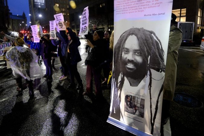 A group of two dozen activists briefly blocks traffic during a rally outside the Philadelphia district attorney’s office in December. The group is urging District Attorney Larry Krasner not to challenge a Common Pleas Court ruling that allows Mumia Abu-Jamal to file an appeal of his murder conviction. (Bastiaan Slabbers for WHYY)