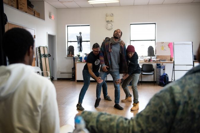 Dwight Dunston (center) drags himself forward as Toby Fraser (left) and Omi Masika (right) hold him back during an exercise at a masculinity workshop held at Lutheran Settlement House on Sunday, October 28, 2018. (Kriston Jae Bethel for WHYY)