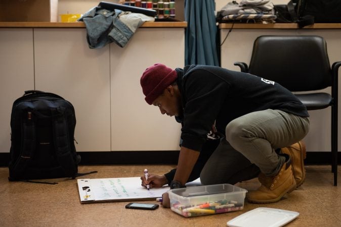 Omi Masika prepares a sign for the reception following a masculinity workshop held at Lutheran Settlement House on Sunday, October 28, 2018. (Kriston Jae Bethel for WHYY)