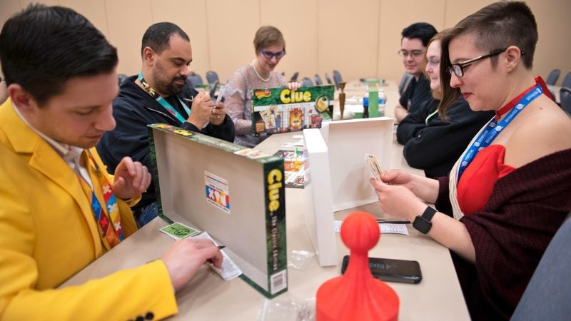 A group of convention goers, some dressed as Colonel Mustard, Miss Scarlett and Mrs. Peacock, participate in a Clue tournament at PAX Unplugged. (Kriston Jae Bethel for WHYY)