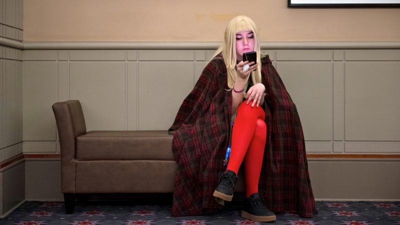 Cassie Silverman checks her phone while taking a break during PAX Unplugged. (Kriston Jae Bethel for WHYY)