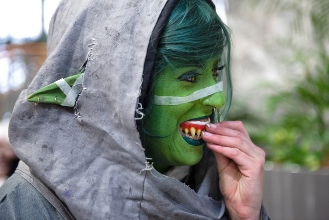 Jenna M. affixes artificial teeth as part of her costume based on the web series Critical Role. Many cosplayers use a partial or online name to separate their work and personal lives from their costumed identities. (Kriston Jae Bethel for WHYY)