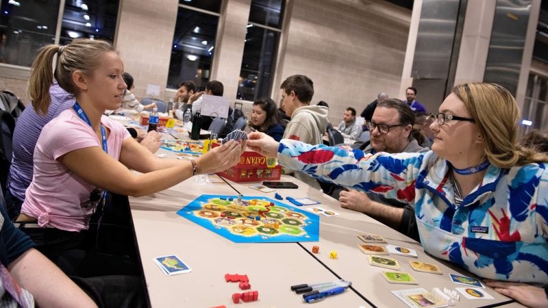 Betsy Chilcoat draws a card from Christa Goad during the first preliminary event of the national qualifier for Settlers of Catan at PAX Unplugged. (Kriston Jae Bethel for WHYY)