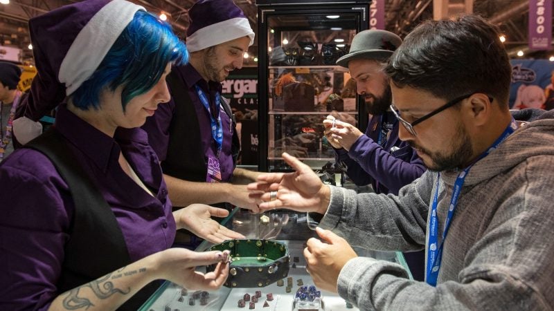 Edwin Morales takes a die out for a test roll at Level Up Dice, one of the many vendors on display at PAX Unplugged. (Kriston Jae Bethel for WHYY)