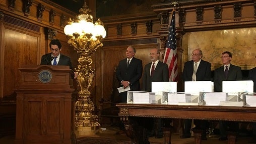 Members of the commission that studied the pension, standing behind binders full of documents. (Katie Meyer/WITF)