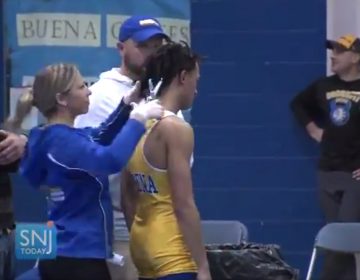 In this image taken from a Wednesday, Dec. 19, 2018 video provided by SNJTODAY.COM, Buena Regional High School wrestler Andrew Johnson gets his hair cut courtside minutes before his match in Buena, N.J. (Michael Frankel/SNJTODAY.COM via AP)