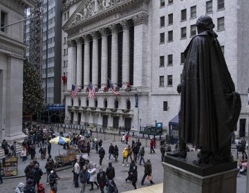 People stand near a statue of George Washington, adjacent to the New York Stock Exchange, background, Saturday, Dec. 22, 2018, at the closed Federal Hall National Memorial in New York.   Now in its 10th year, America's economic expansion still looks sturdy. Yet the partial shutdown of the government that began Saturday has added another threat to a growing list of risks. (Craig Ruttle/AP Photo)