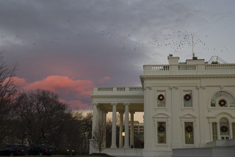 The setting sun illuminates clouds behind the White House during a partial federal shutdown, Saturday, Dec. 22, 2018, in Washington. The partial federal shutdown was expected to drag into Christmas as President Donald Trump and congressional leaders remained stuck in a standoff over his border wall with Mexico. (AP Photo/Alex Brandon)