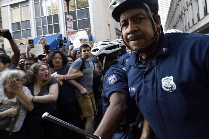 Philadelphia police officers clear protesters from the path of a government vehicle, driven by United States Secret Service agents, during Vice President Mike Pence's visit to an event organized by Republican Governors Association at a Rittenhouse Square hotel on June 19, 2018. (Bastiaan Slabbers for WHYY)