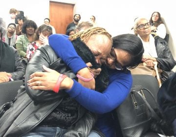 Sharon Osburn (left) fights back tears after telling prison officials about her son's sudden transfer to a Pennsylvania prison. Osburn is being comforted by state Rep. Sherry Dorsey Walker of Wilmington. (Cris Barrish/WHYY)
