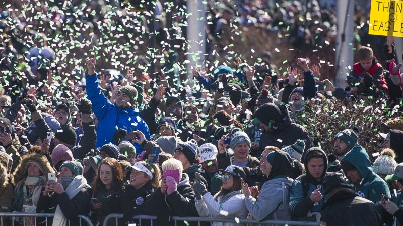 Fans are showered with confetti from passing team buses during the Super Bowl parade in Philadelphia, Feb. 8, 2018. (Jonathan Wilson for WHYY)