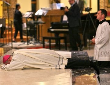 Bishop Dennis Sullivan prostrates himself at the altar during an evening of prayer for the victims of sexual abuse by Catholic clergy on Sept. 28, 2018, in Blackwood, New Jersey. (Miguel Martinez for WHYY)